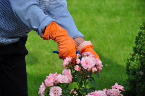 Worker wearing high-visibility PPE mowing a hedge edge